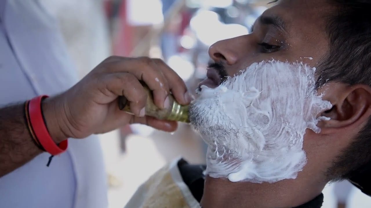 A street barber shaves a man, a frame from Routine